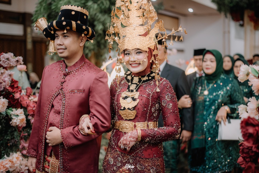 Kirab pengantin memasuki ruang resepsi didampingi keluarga besar berbalut busana adat merah marun keemasan