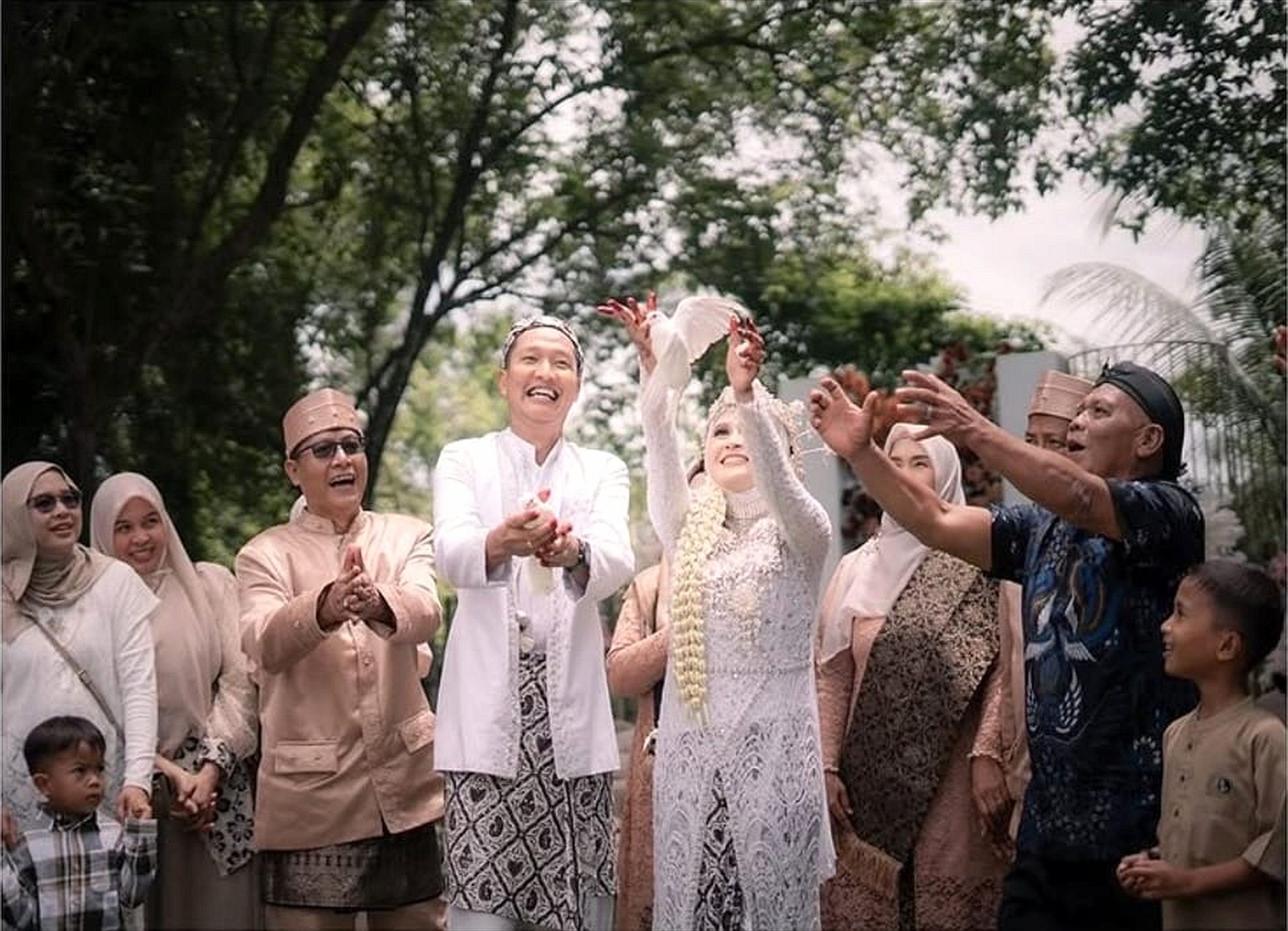 Prosesi pelepasan sepasang merpati putih bersama keluarga besar di area outdoor